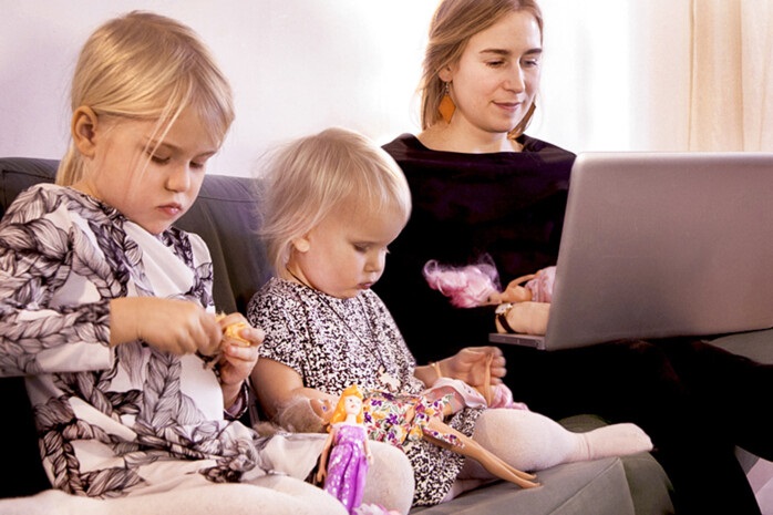 Mamma och två barn sitter i soffan.